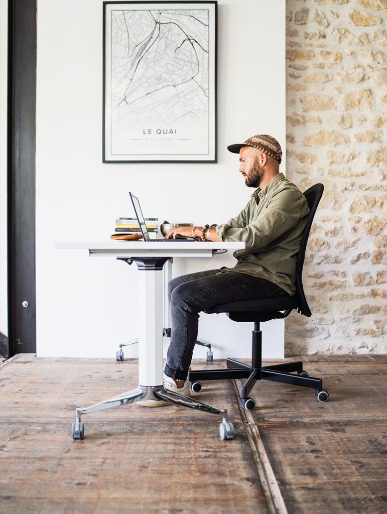 Emeric SIMON créateur de sites web concentré sur son ordinateur dans un espace de travail design